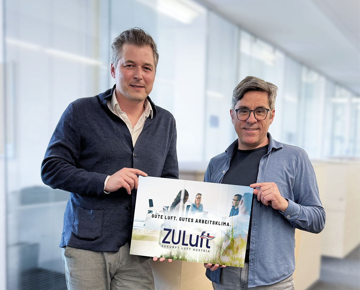 Foto von Wolfgang Hucek und Andreas Jäger, wo sie gemeinsam einen ZULuft-Flyer in der Hand halten